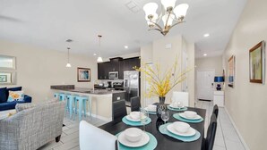 A modern kitchen with dark cabinets, a central island, and a dining area with a black table set for four.