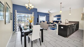 A modern kitchen with a central island, a dining area with a table and chairs, and a living area with sofas and a coffee table.