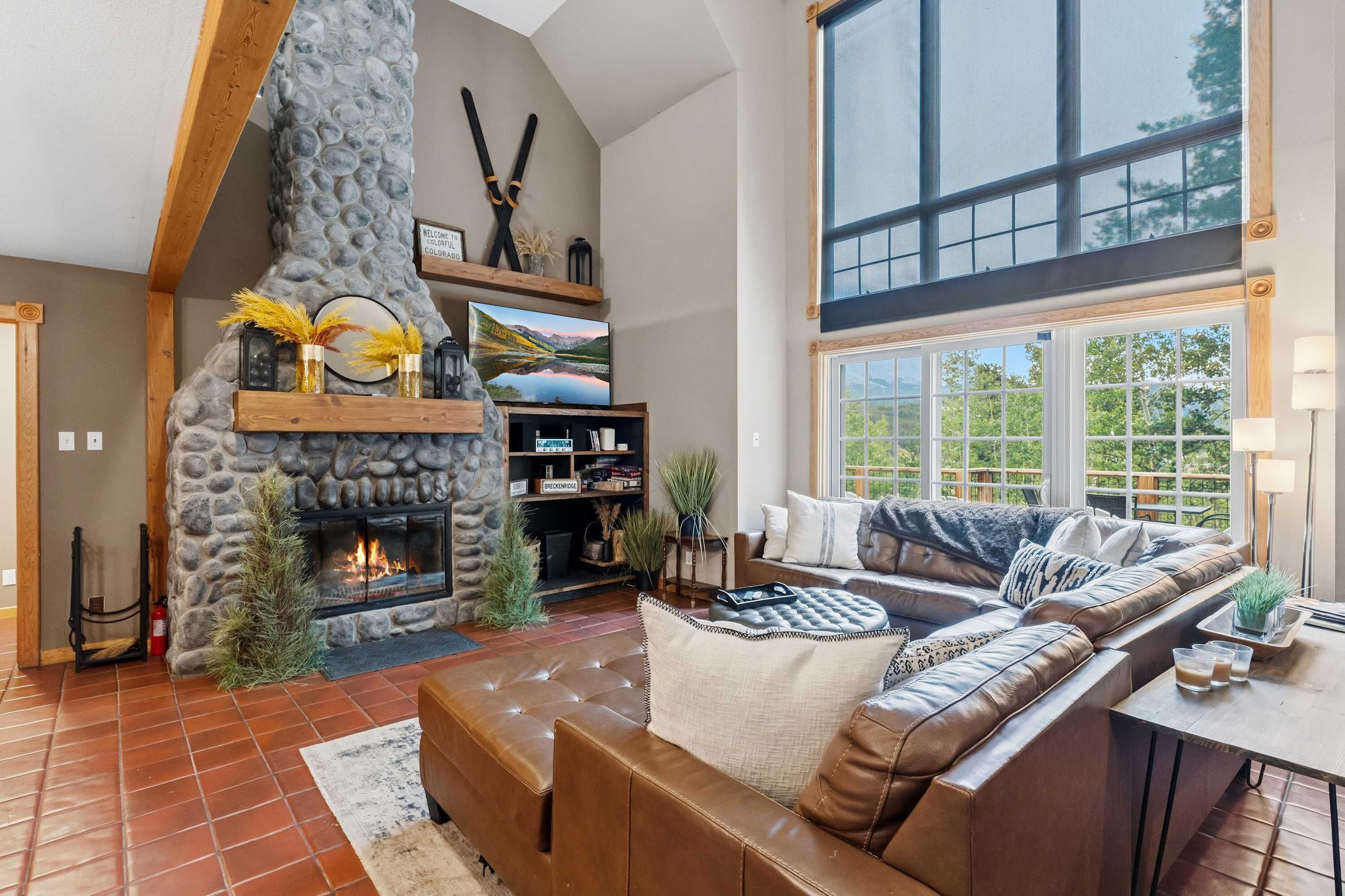 A spacious living room with a stone fireplace, a large window, and a leather sofa.