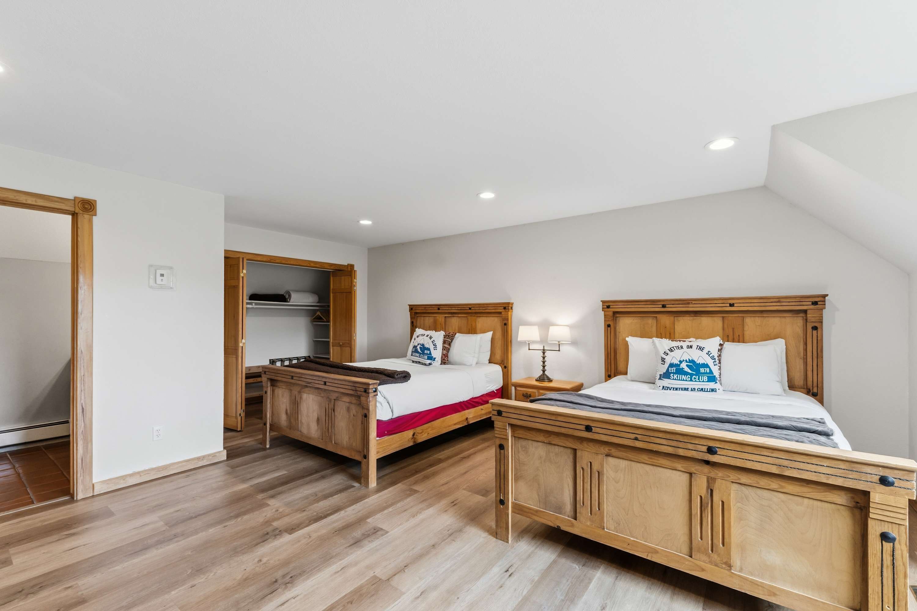 Une chambre à coucher avec deux lits en bois, une armoire en bois et un bureau en bois.