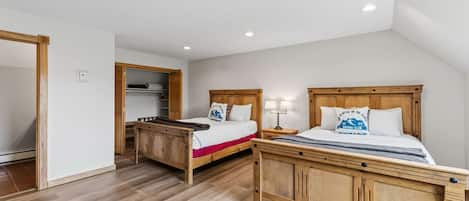 Un dormitorio con dos camas de madera, un armario de madera y un escritorio de madera.