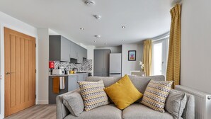 A modern living room with a grey sofa, two patterned cushions, and a wooden door.