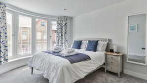 A bedroom with a bed, bedside table, and a window with curtains.