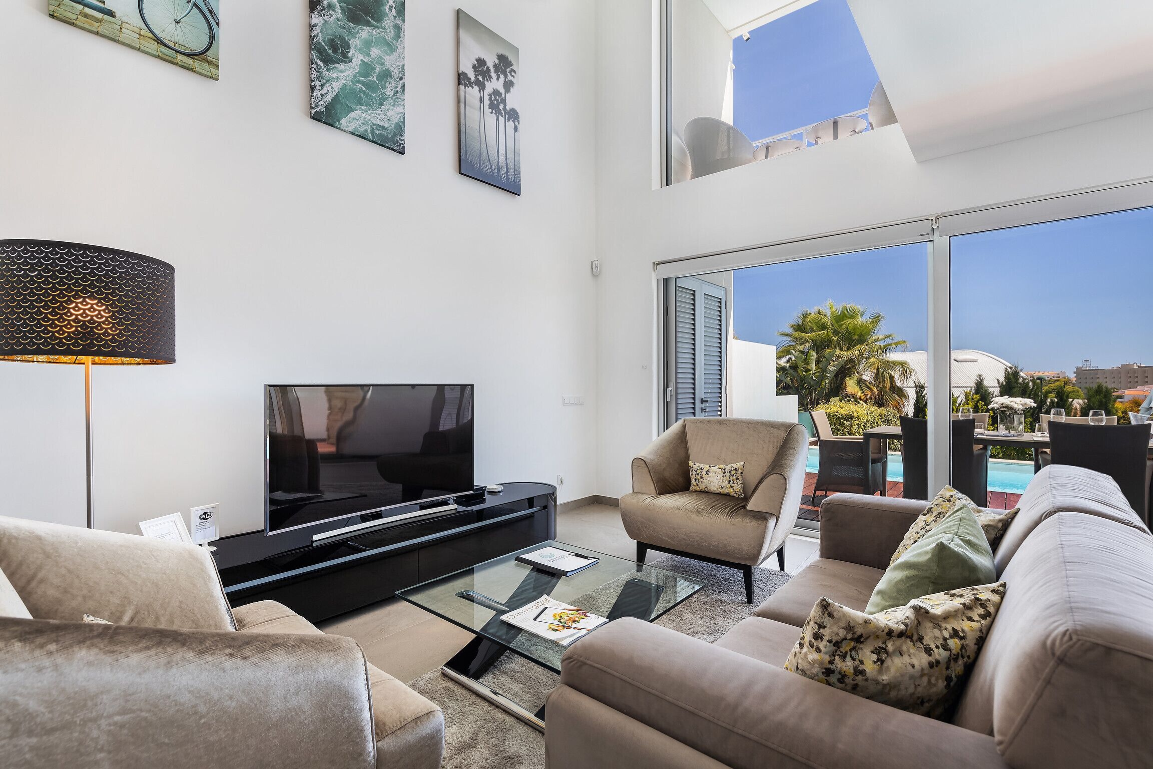 A modern living room with a flat-screen TV, comfortable seating, and a glass coffee table.