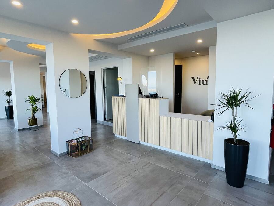 A modern reception area with a curved reception desk, a large mirror, and a reception desk with a nameplate.