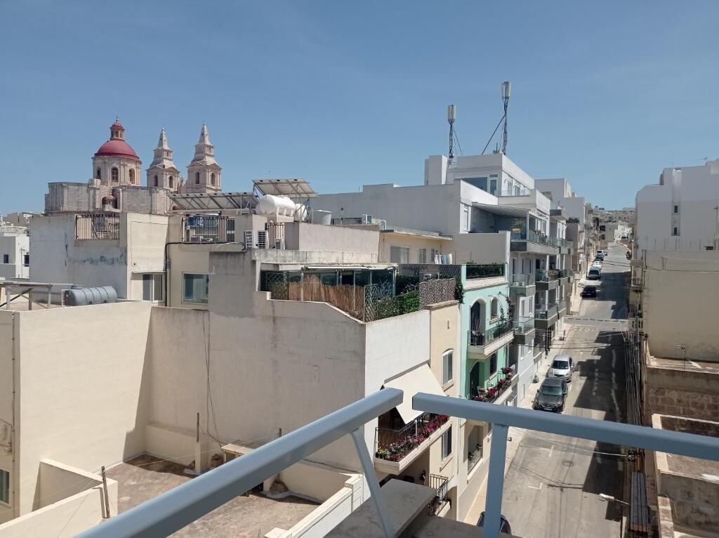 Zona residencial con edificios, una calle e iglesia de tejados rojos.