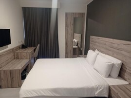 Ein Hotelzimmer mit Bett, Schreibtisch, Stuhl und Fernseher.