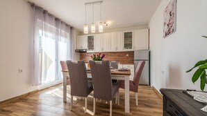 A modern kitchen with white cabinets, a wooden countertop, and a dining area with two chairs and a table. - Little House by the Sea, Beachfront, Parking, WiFi (Preko)