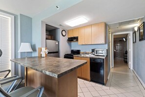 A kitchen with granite countertops, wooden cabinets, a refrigerator, a microwave, and a dishwasher.