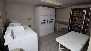 A laundry area with a washing machine, dryer, and a vending machine.