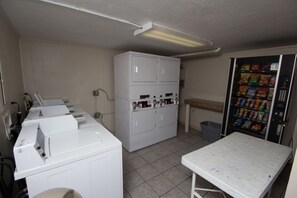 Un espace buanderie équipé d’un lave-linge, d’un sèche-linge et d’un distributeur automatique.