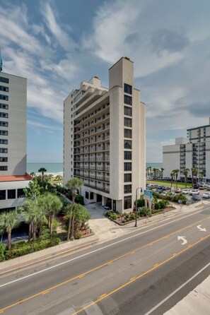 A high-rise hotel with multiple balconies, a parking lot, and a view of the ocean. - Hosteeva Oceanview Condo With Pool (Myrtle Beach)