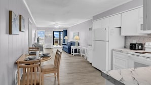 Une cuisine moderne avec des meubles blancs, un plan de travail en marbre et un coin repas comprenant une table et des chaises en bois.