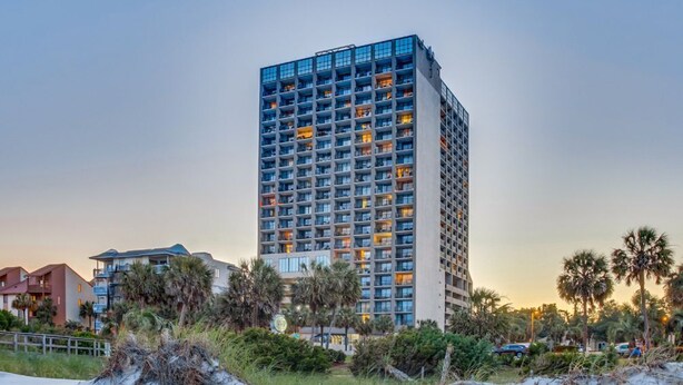 A high-rise hotel with multiple floors, balconies, and a beachside location.