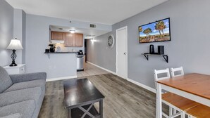 Eine moderne Wohnung mit Wohnzimmer, Essbereich, Küche und einem Flur, der zum Schlafzimmer führt.