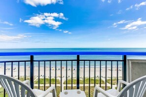 A balcony with a view of the beach and ocean.