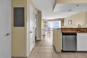 A modern kitchen with a dishwasher, a dining area with a table and chairs, and a view through the window.