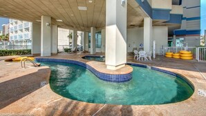 Ett utomhusområde med en pool, utformat med en böjd design, omgivet av en täckt gångväg och sittplatser.