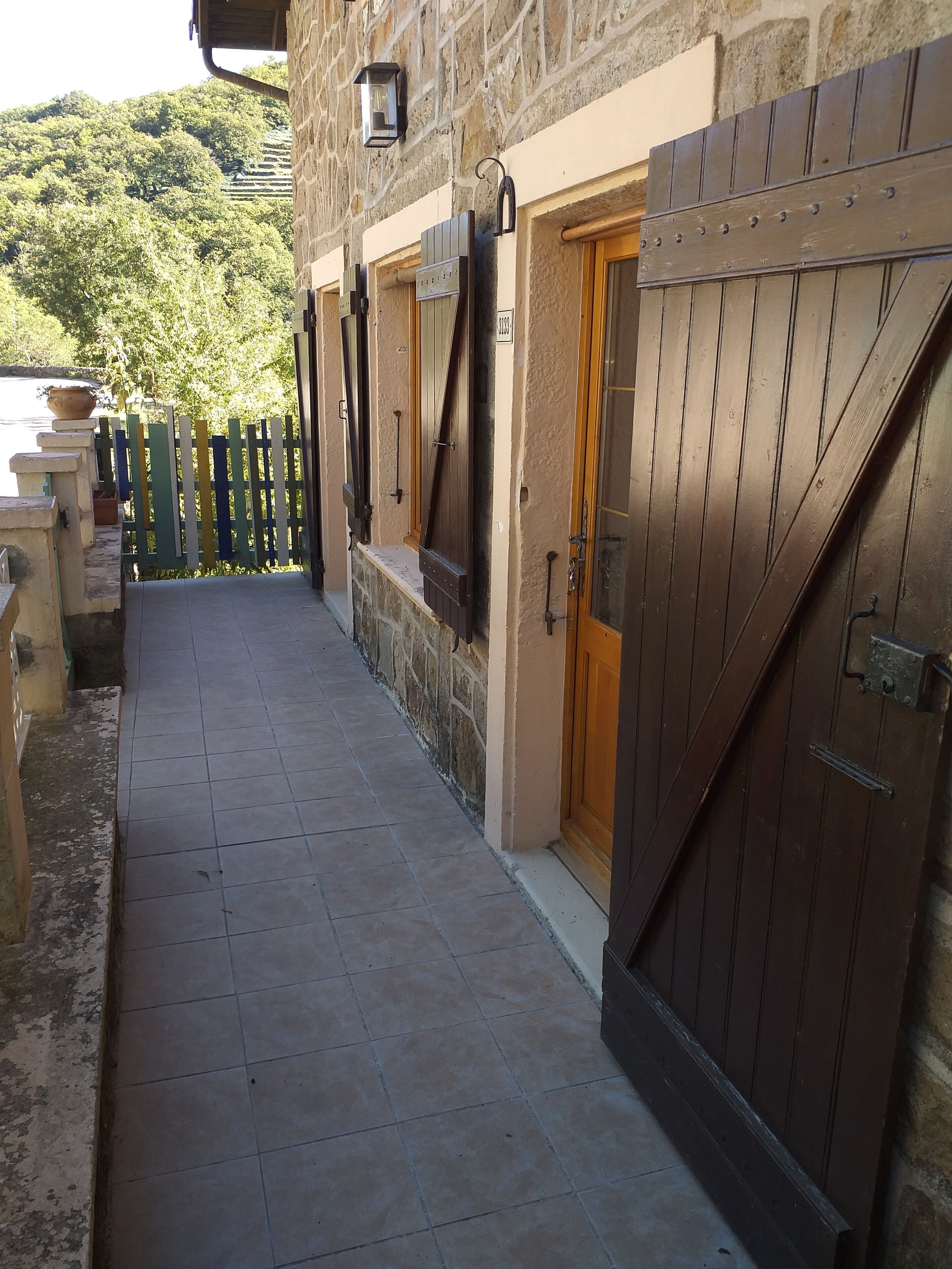 A stone building with a tiled walkway leading to a wooden door.