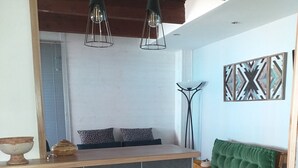 A modern kitchen with a wooden countertop, two hanging pendant lights, and a built-in seating area with a green upholstered sofa and a colorful stool.