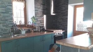 A modern kitchen with teal cabinets, a wooden countertop, a built-in stove, and a large window.