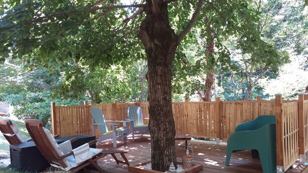 A wooden deck with two Adirondack chairs, a small table, and a green play structure.