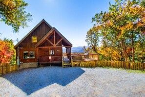A wooden cabin with a porch, surrounded by a gravel driveway and a wooden fence. - Mountain-View Cabin w/ Game Loft, Hot Tub & Fireplaces (Sevierville)