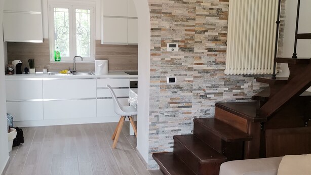 A modern kitchen with white cabinets, a stone backsplash, and a window with a view. - Nemo's Home (Arcola)
