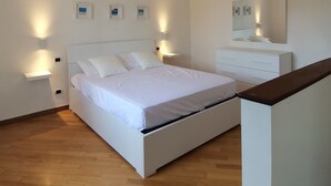A bedroom with a large bed, bedside tables, a dresser, and a mirror. - Nemo's Home (Arcola)
