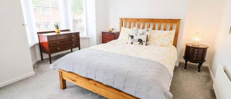 Una camera da letto con un letto in legno, una scrivania, una sedia, un comodino e una finestra con persiane.