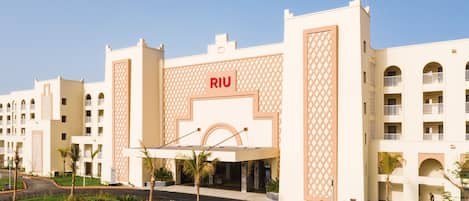 Un hotel con un llamativo letrero de 'RIU', varios balcones y un jardín bien cuidado.