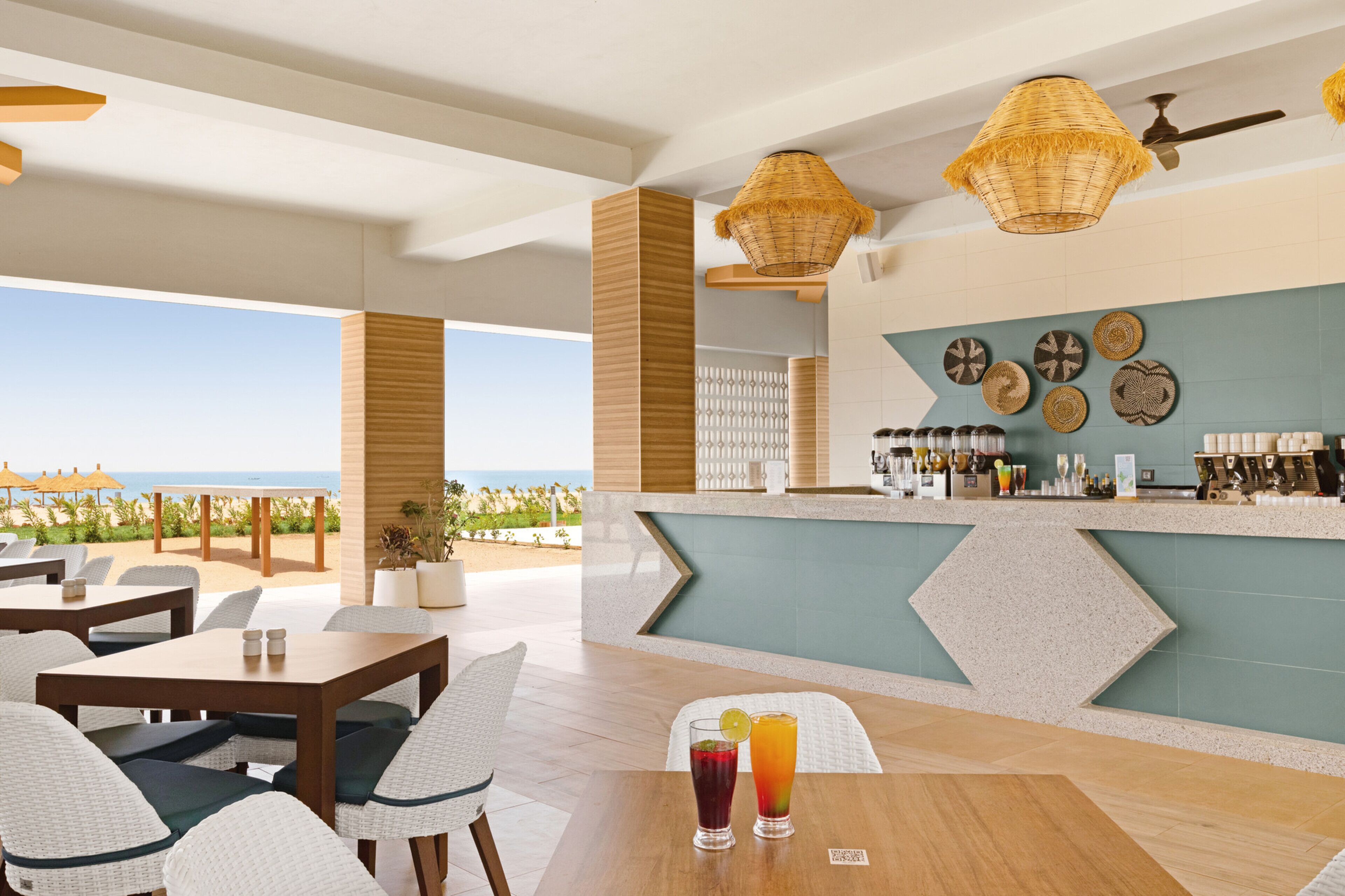 A bar area with a view of the ocean, outdoor seating, and a buffet counter.