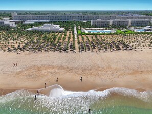 A resort with a beachfront, a pool area, and a large building complex.