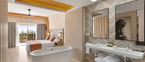 Habitación de hotel moderna con una bañera grande, una cama doble, una zona de estar con vistas y un espejo amplio.
