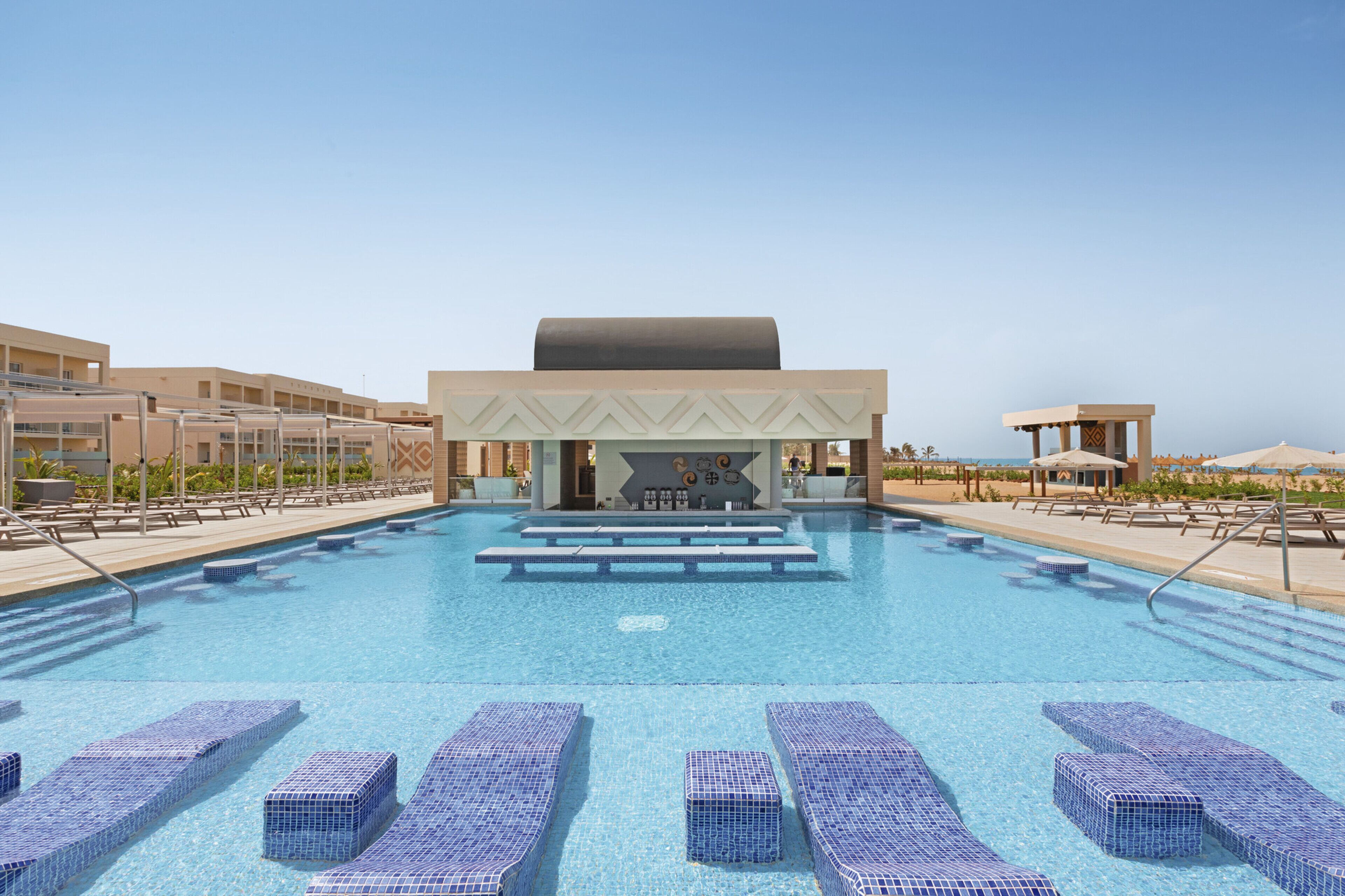 A swimming pool with lounge chairs and a bar area.