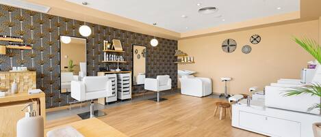 A modern salon with a wooden floor, white chairs, and a large mirror.