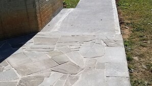 Un sendero de piedra que conduce a un edificio de fachada de concreto.