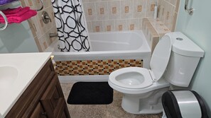 A bathroom with a bathtub, toilet, and sink.