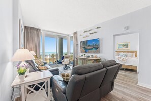 A modern hotel room with a balcony, a bed, a desk, and a seating area. - Avista Resort 220-3BR/3BA Oceanfront Condo in Ocean Drive (North Myrtle Beach)