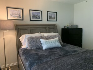 A bedroom with a bed, a nightstand, a dresser, and three framed pictures on the wall.