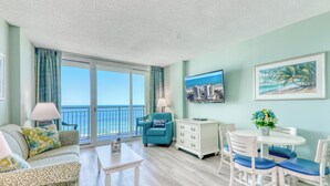 Une pièce comprenant un canapé, une table basse, une table à manger avec des chaises, un buffet et un tableau accroché au mur.