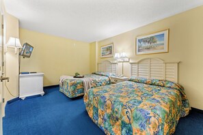 Une chambre d’hôtel avec deux lits, un bureau, une lampe et un téléviseur.
