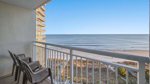 A balcony with a view of the beach and ocean.