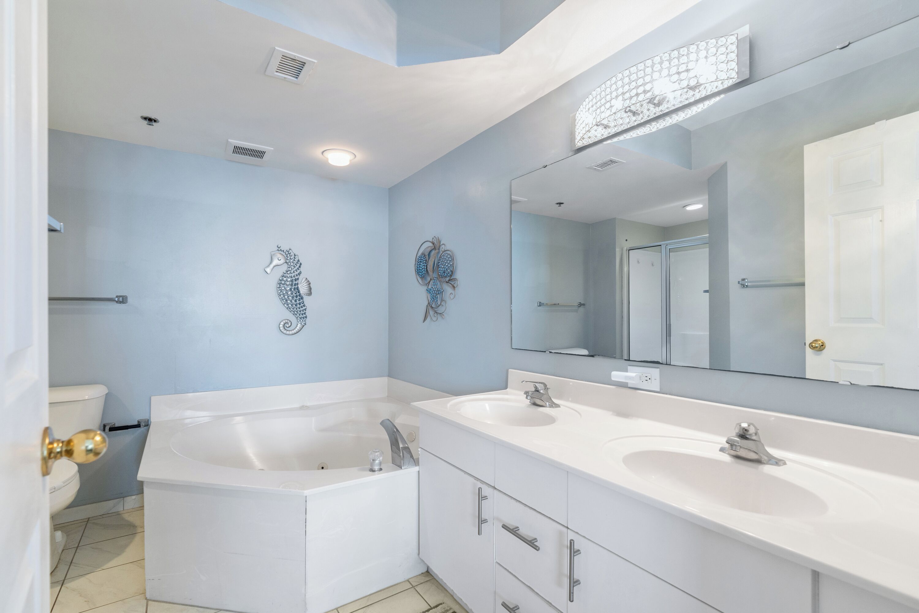 A modern bathroom with a large bathtub, two sinks, and a large mirror.