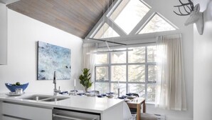 Een moderne keuken met een groot eiland, een eetruimte met uitzicht en een dakraam.
