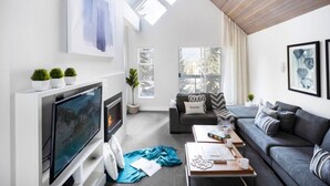 Een moderne woonkamer met een flatscreen televisie, een open haard, een bank en een salontafel.