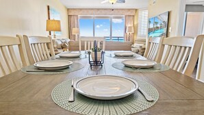 A dining table set for six with a view of the ocean through large windows. - Bahama Sands Luxury Villas PH6-3BR/3BA Oceanfront condo in Crescent Beach (North Myrtle Beach)