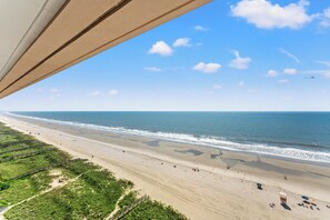 A beach with a wooden boardwalk, a sandy shore, and a clear sky.