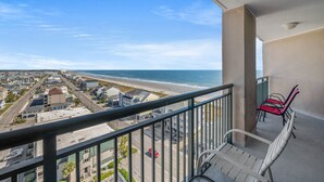 A balcony with a view of the beach and ocean, a chair, and a table. - Beachwalk Villas 808-2BR/2BA Condo in Cherry Grove (North Myrtle Beach)
