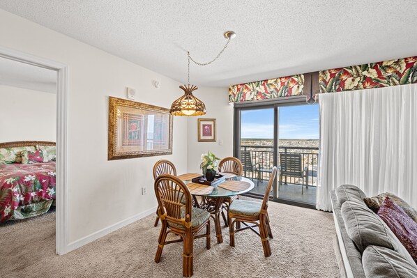 A dining area with a round table, chairs, and a hanging light fixture.